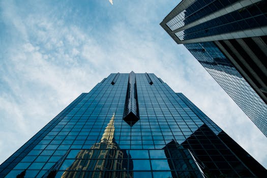 Low angle view of a modern skyscraper with reflective glass facade against a cloudy sky.